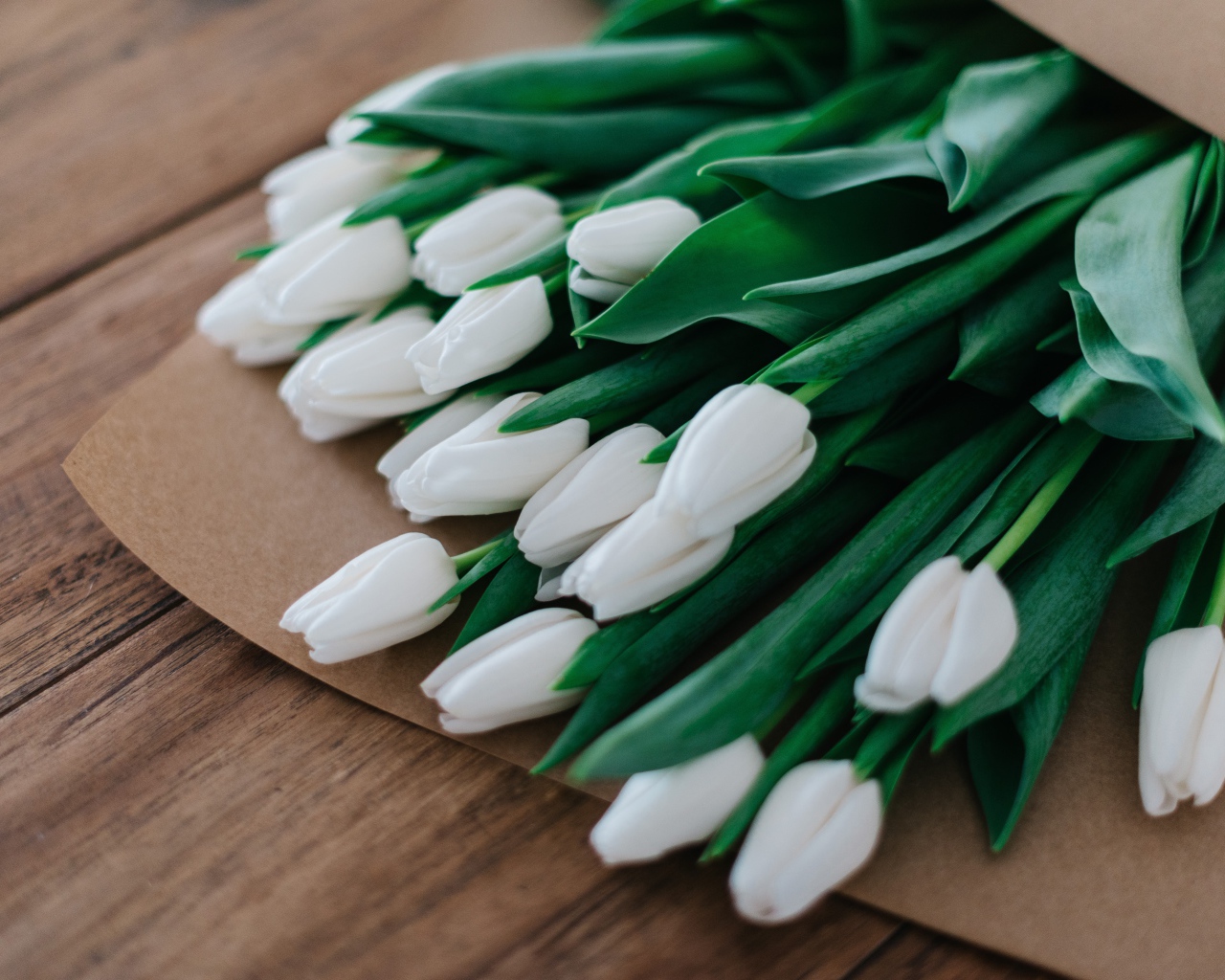 Large bouquet of white tulips in a paper bag