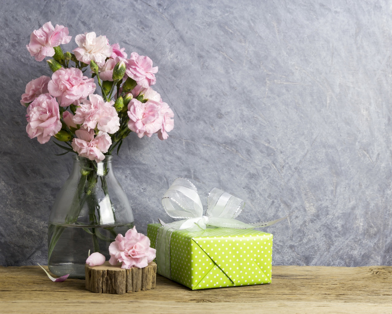 Розовые гвоздики с подарком на сером фоне