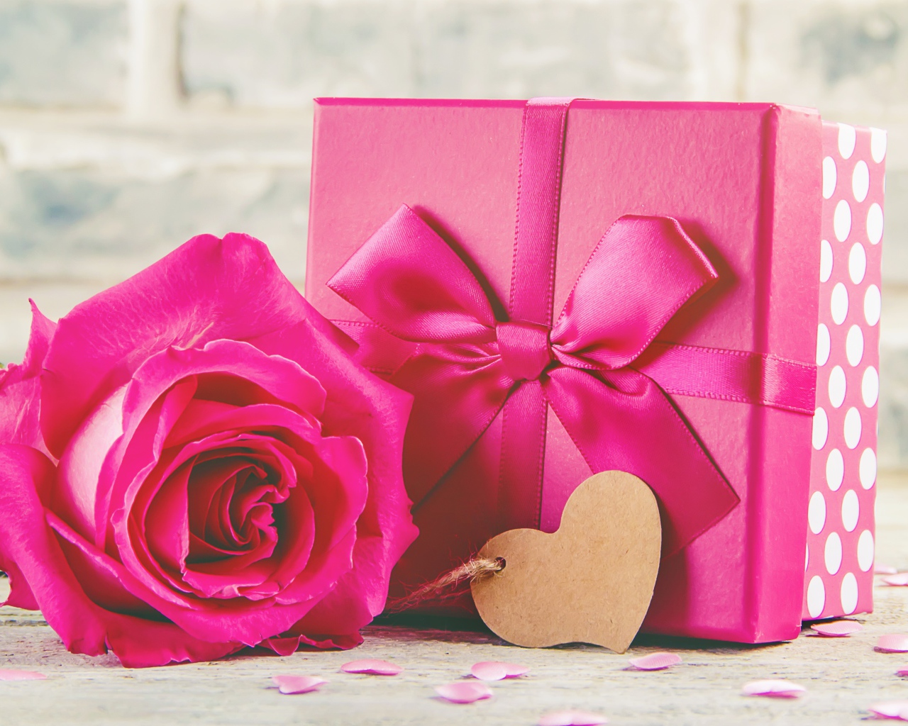 Розовая роза на столе с большим подарком с бантом