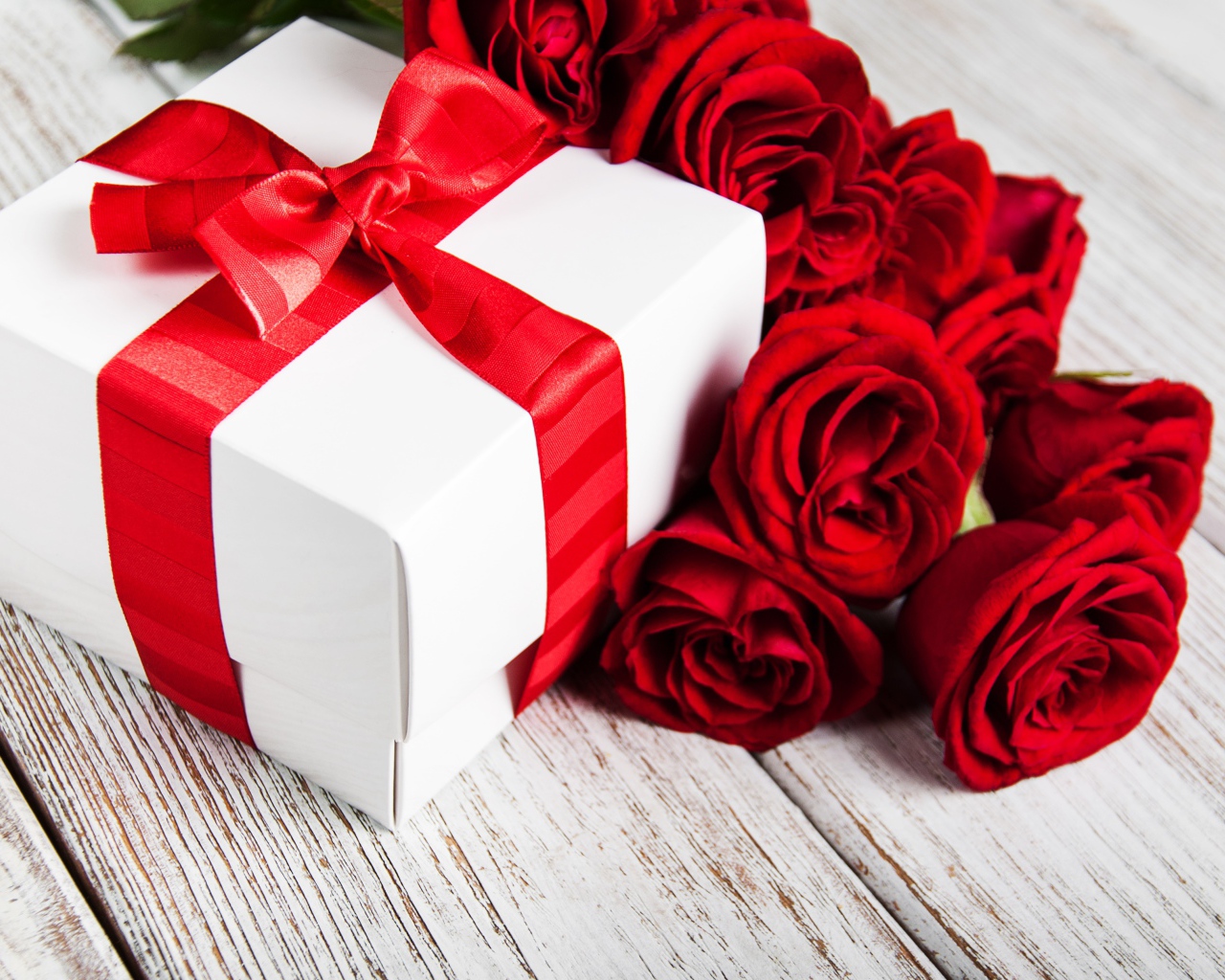 Красные розы на столе с подарком с красной лентой