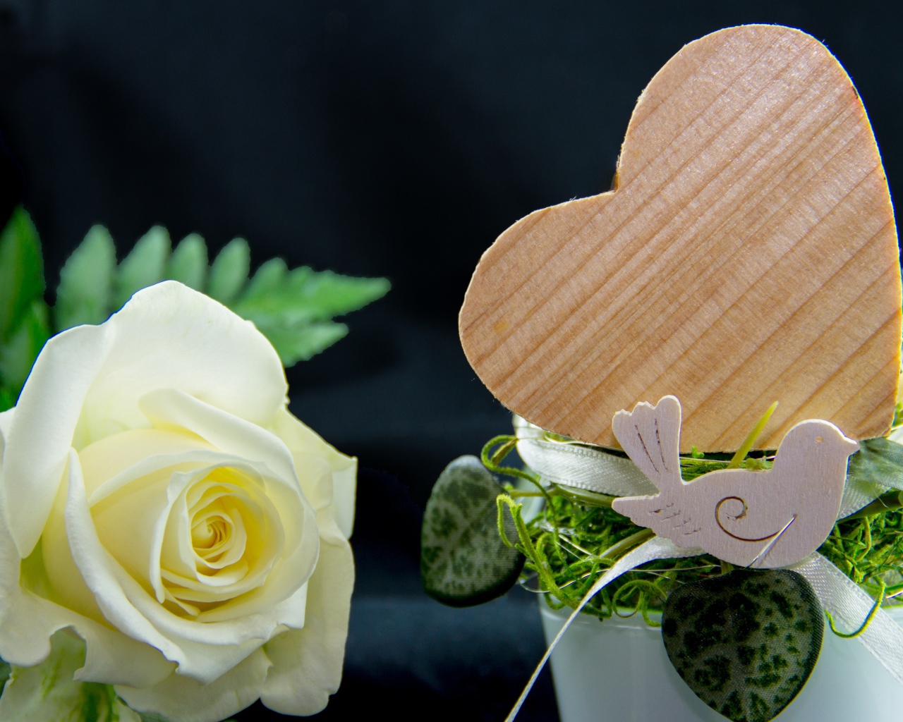 Деревянное сердце и белая роза на столе 