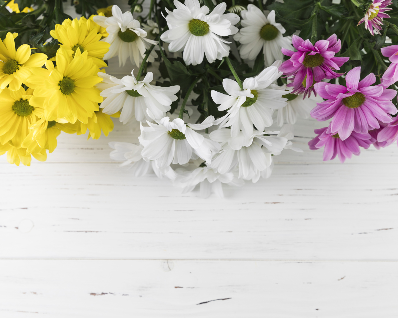 Желтые, белые и розовые хризантемы на белом деревянном столе