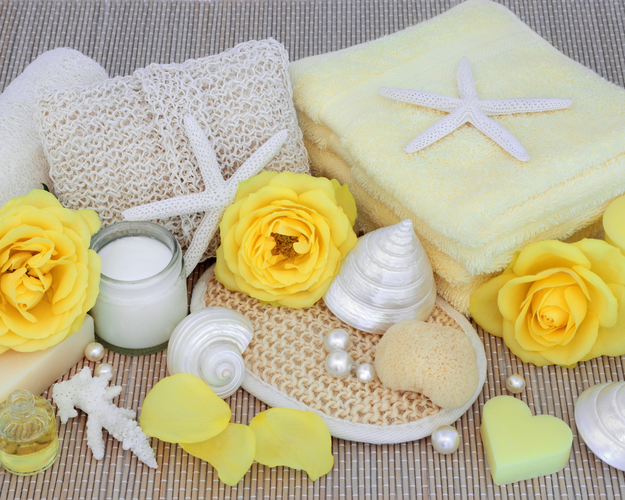 Желтые розы на столе с полотенцем, ракушками и мылом
