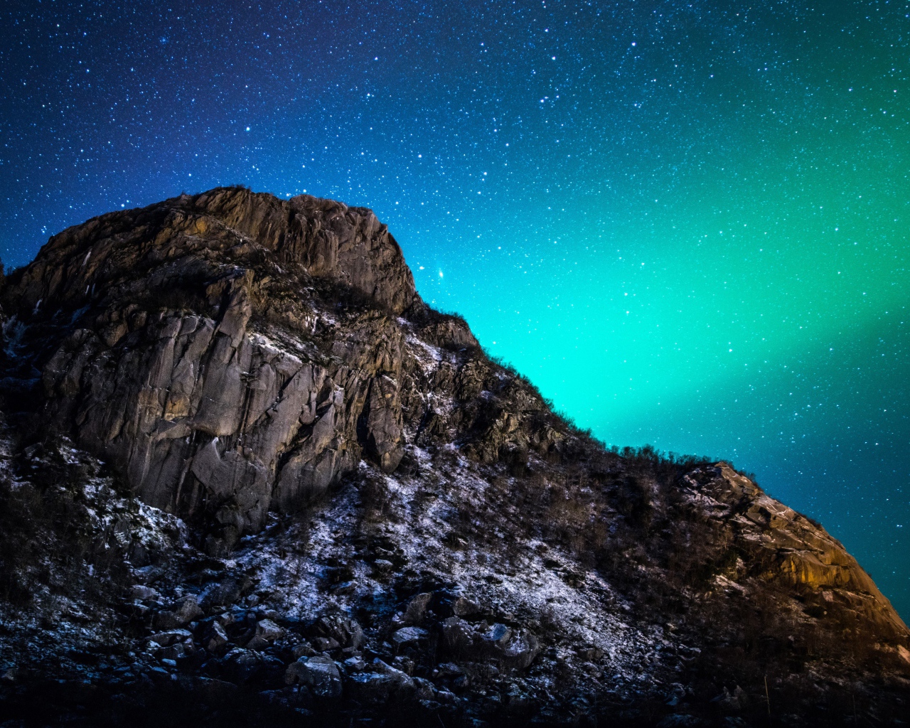 Красивое зеленое полярное сияние в звездном небе над горой 