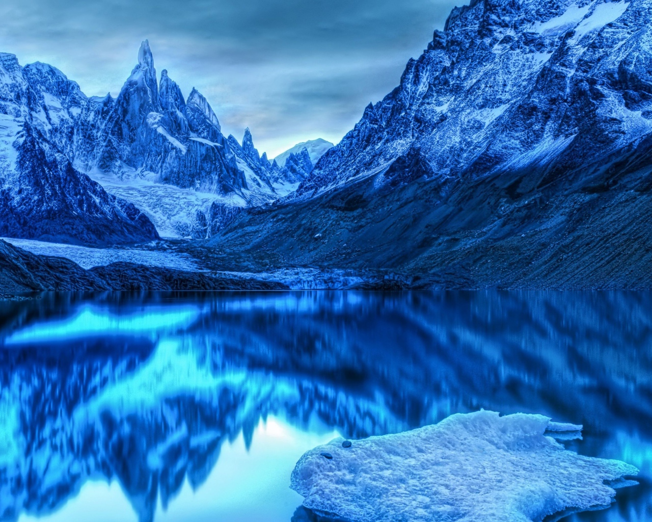 Голубой холодный закат на заснеженными горами у озера 