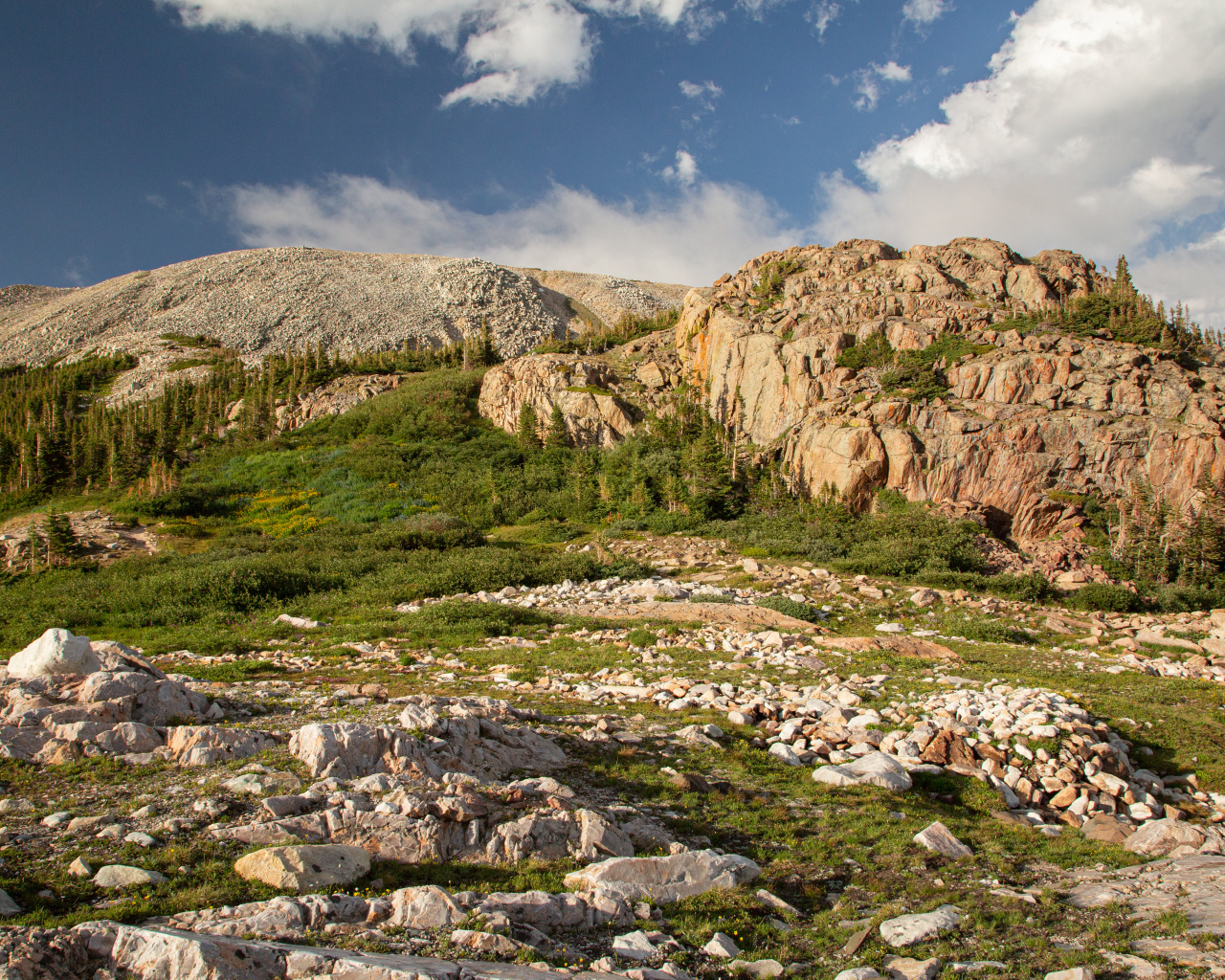 Высокие каменные горы под  голубым небом с белыми облаками