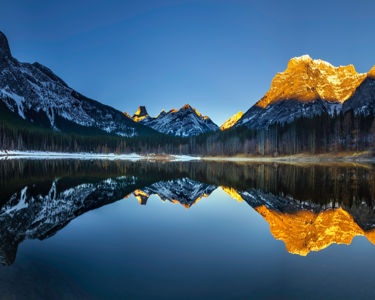 Вершины гор в лучах солнца отражаются в озере
