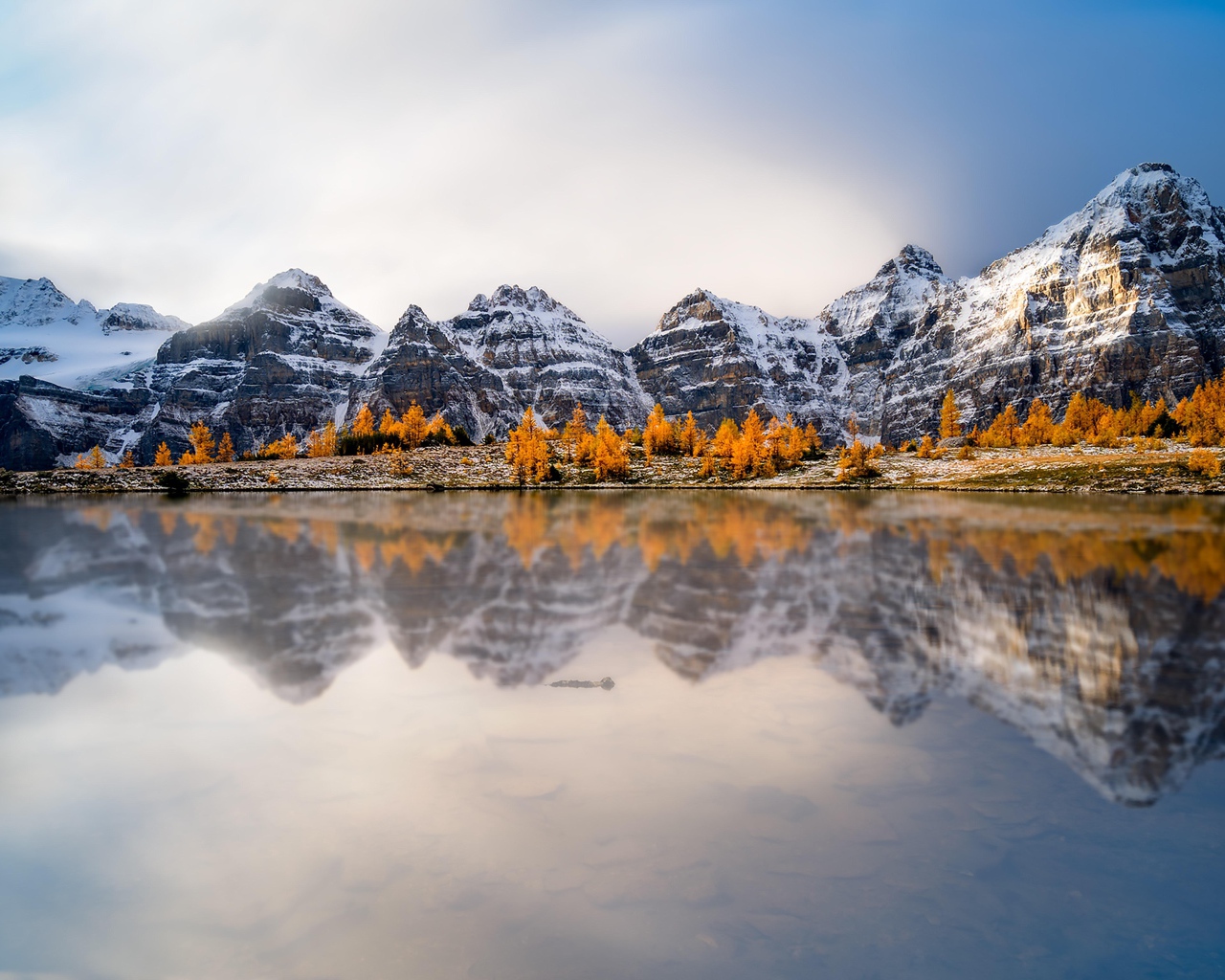 Заснеженные горы отражаются в воде озера 