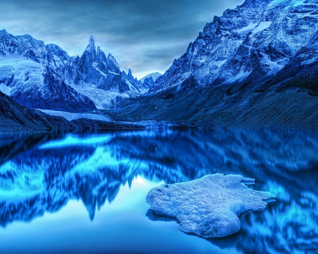 Заснеженные горы отражаются в воде в сумерках