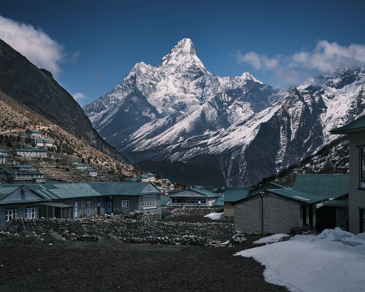 Поселок на фоне заснеженных гор под голубым небом 