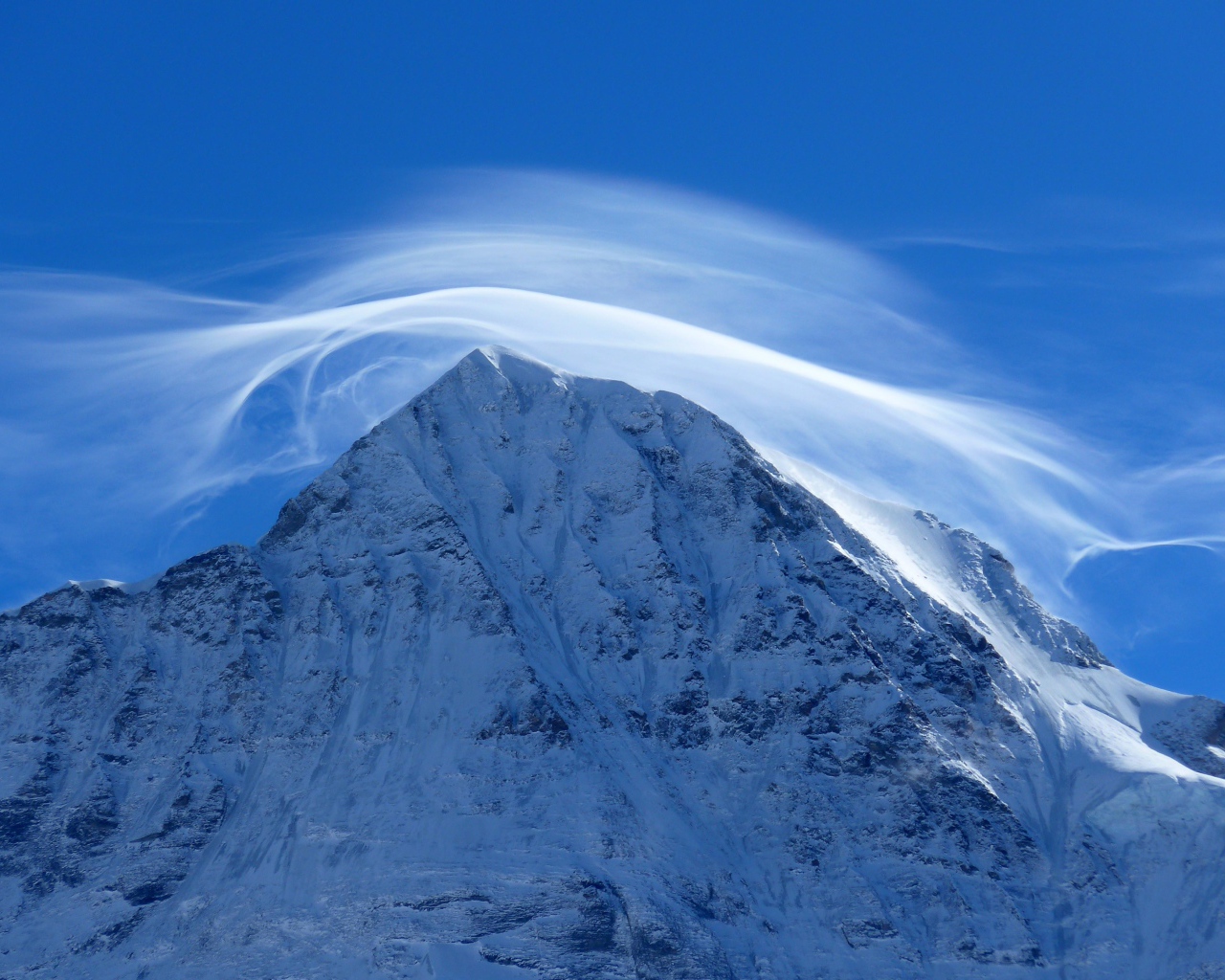 Белое облако в голубом небе над заснеженной горной вершиной