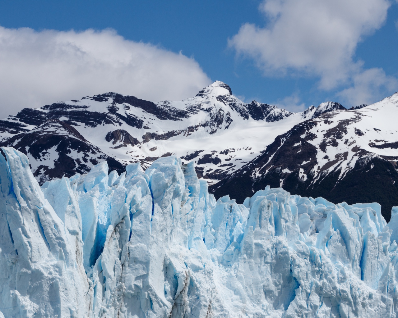 Голубой ледник на фоне заснеженных гор 