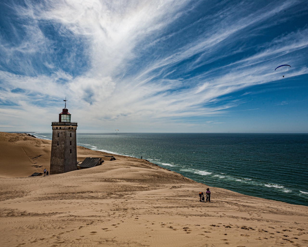 Маяк на песке на берегу моря под голубым небом