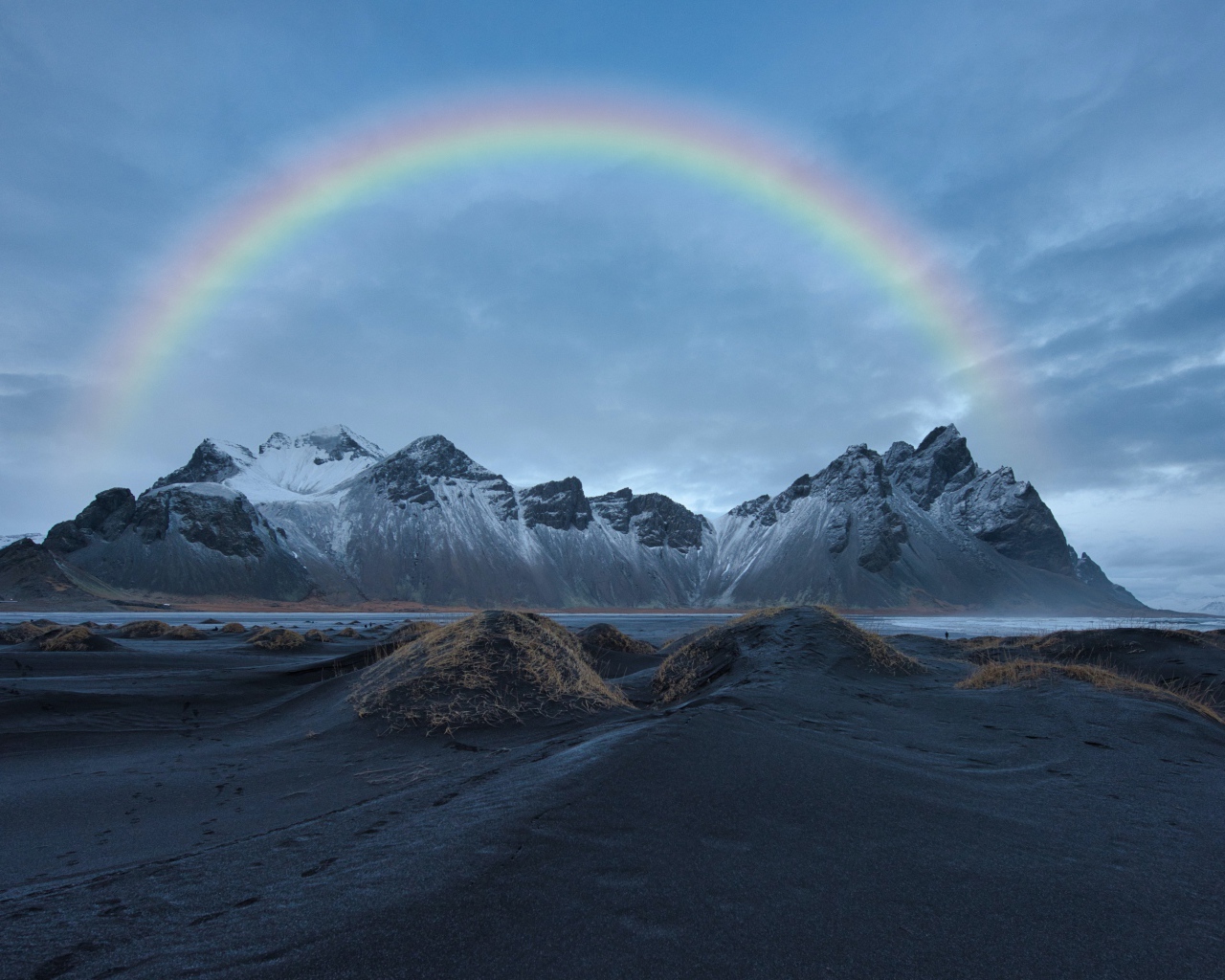 Радуга в небе над высокими горами