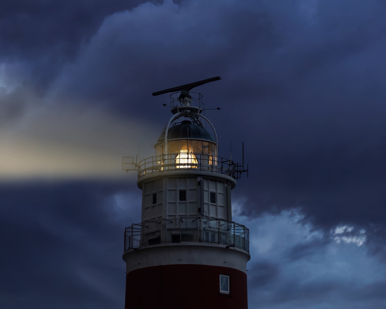 Грозовое небо над включенным маяком ночью