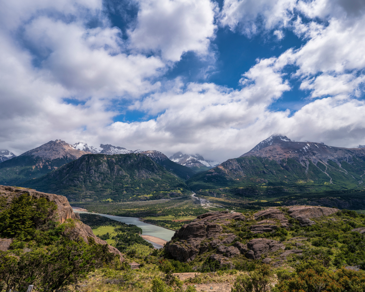 Белые облака в голубом небе над покрытыми зеленью горами