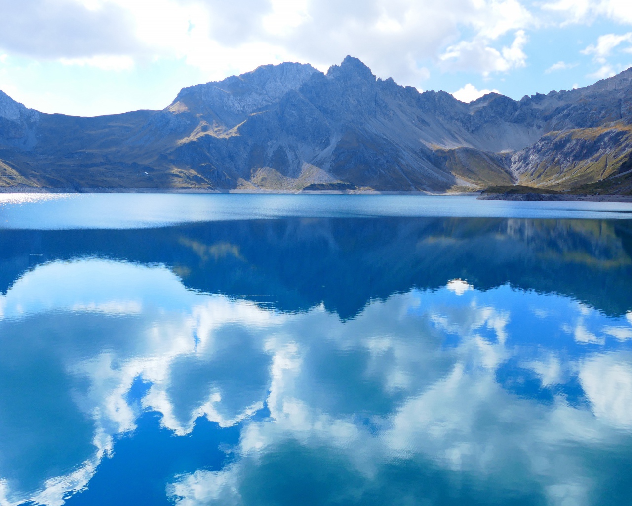 Большое голубое озеро в горах под голубым небом 