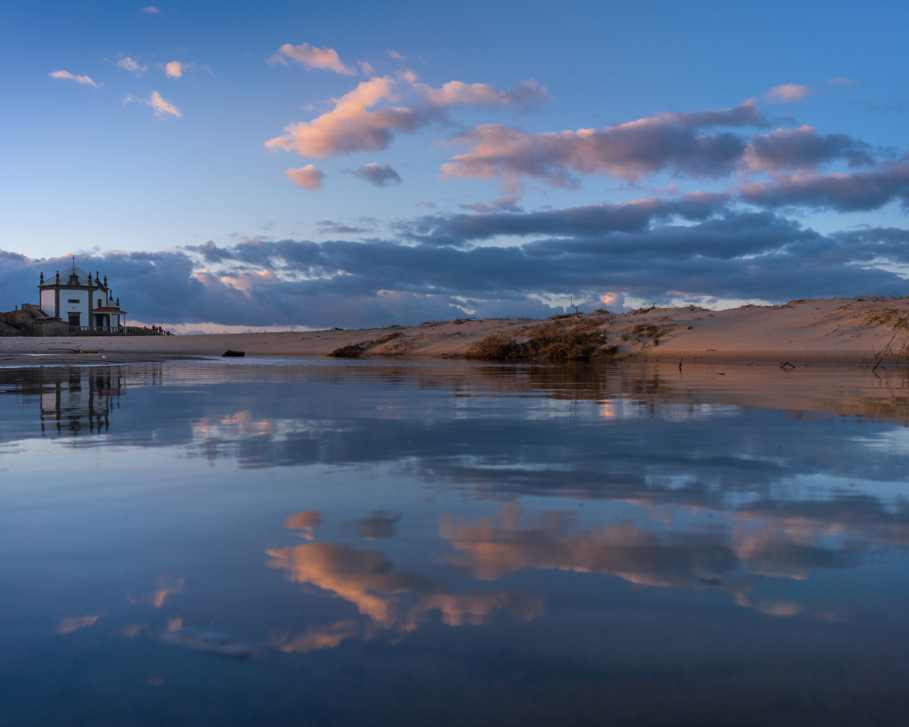 Облака отражаются в спокойной воде озера 