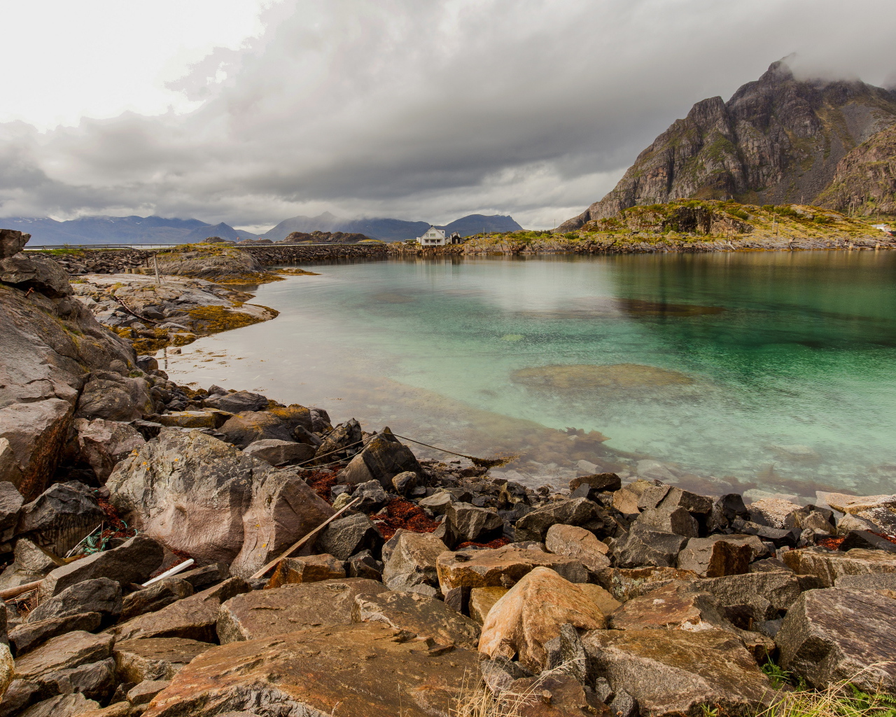 Камни на берегу горного озера под грозовым небом