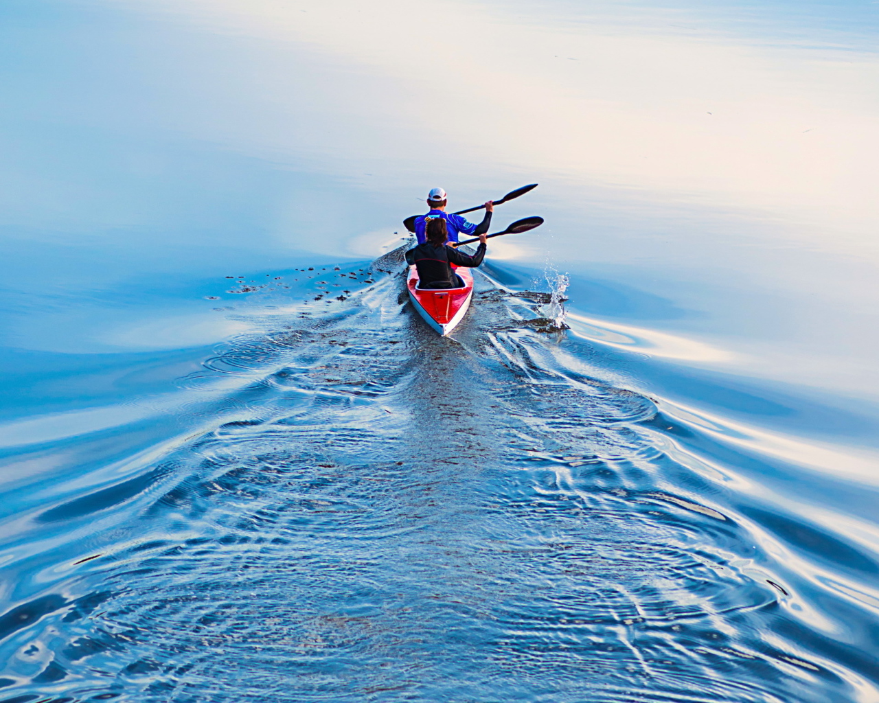 Два спортсмена на лодке плывут по реке 