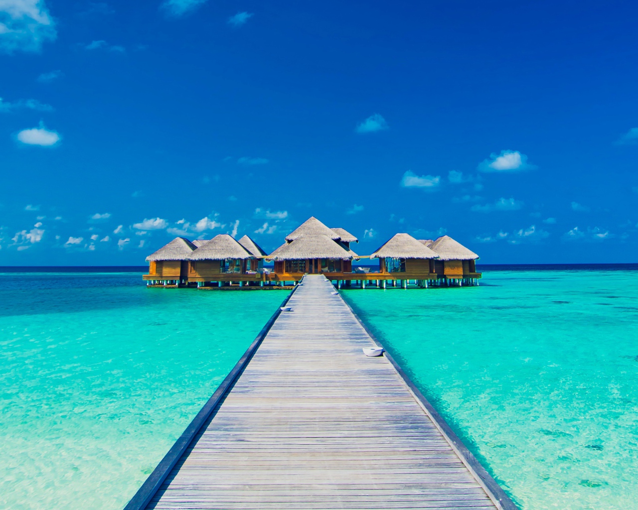 Деревянный мост к домам на сваях в голубом океане 