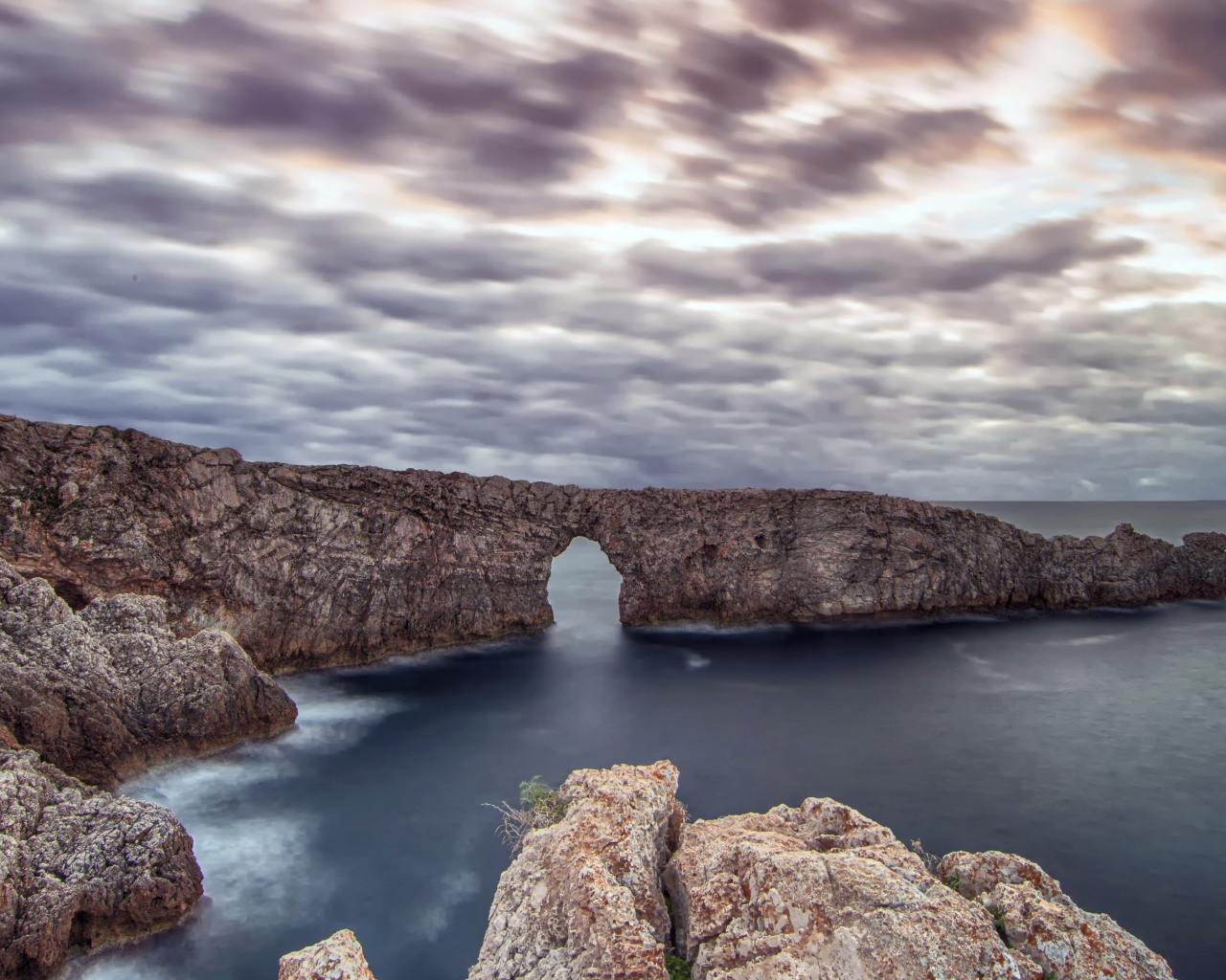 Арка в скале в море под пасмурным небом 
