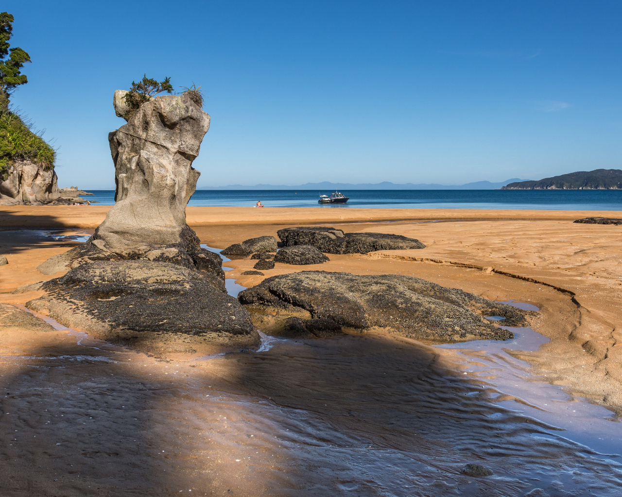 Большие камни на берегу на мокром песке у моря летом 