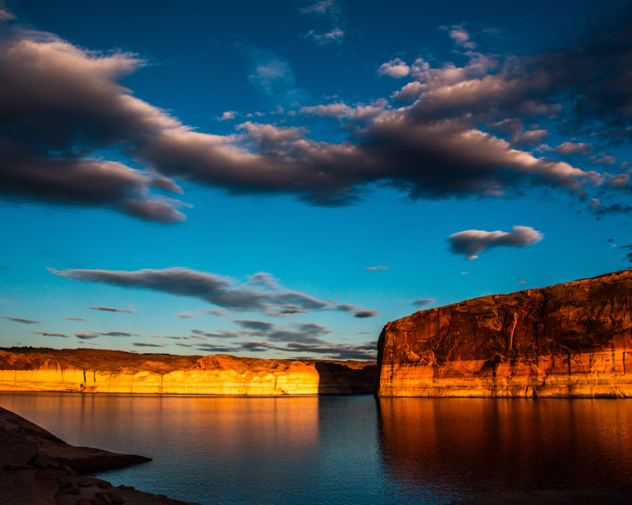 Скалы  в воде под голубым небом с облаками 