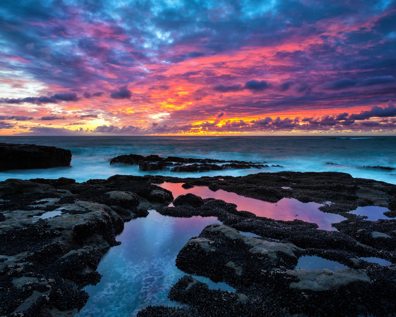 Восход яркого солнца над камнями в море