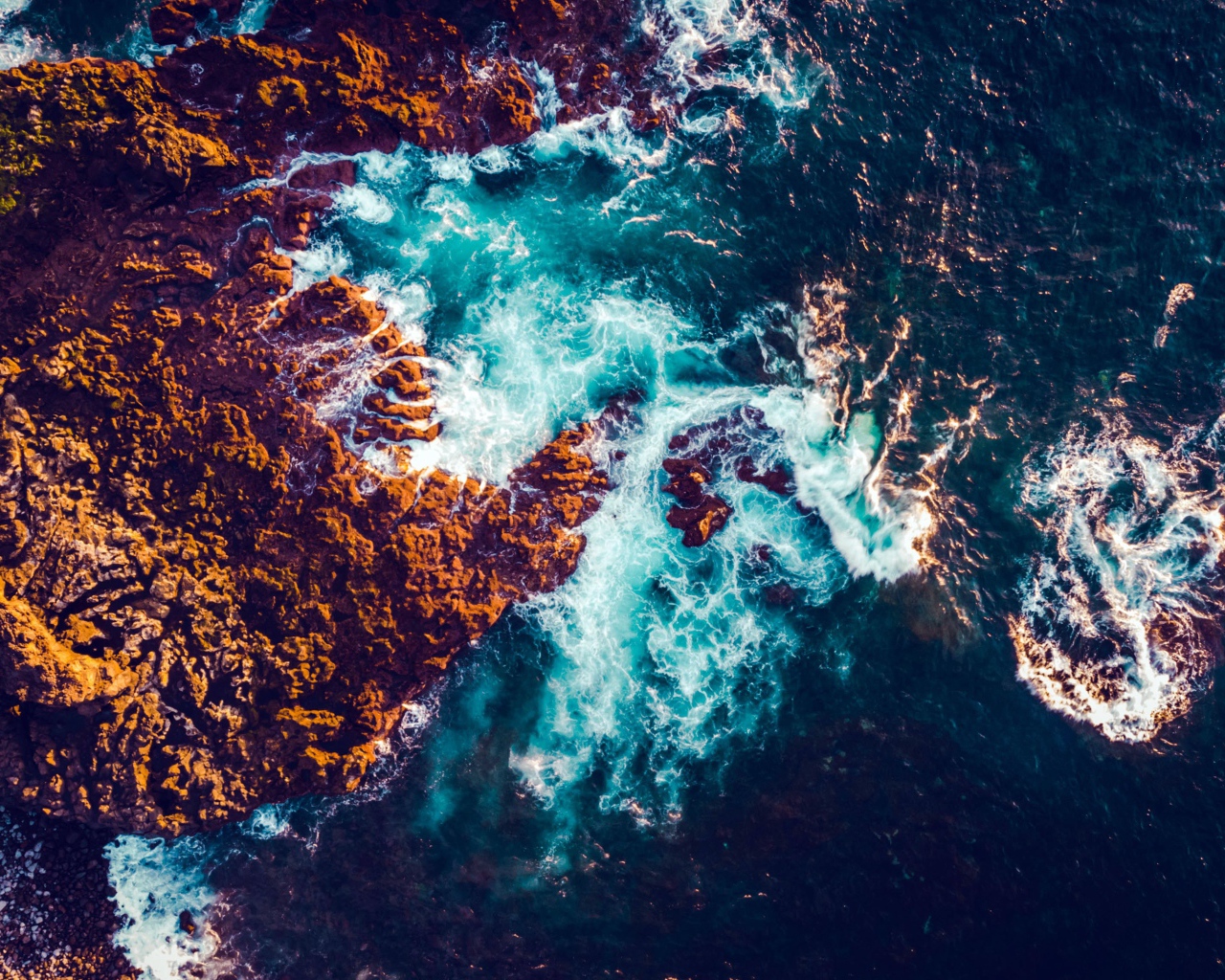 Белые морские волны бьются об камни, вид сверху