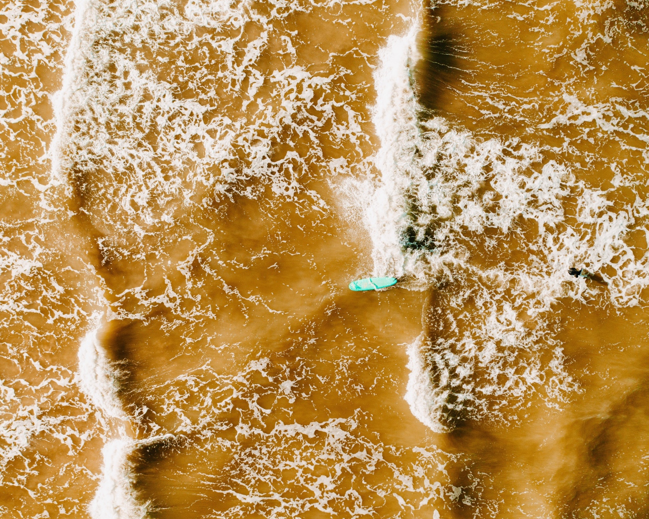 Белые волны на воде поднимают песок