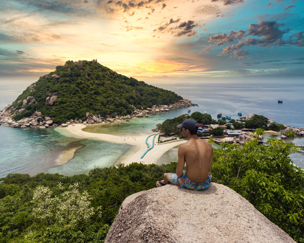 Мужчина сидит на краю скалы на закате 