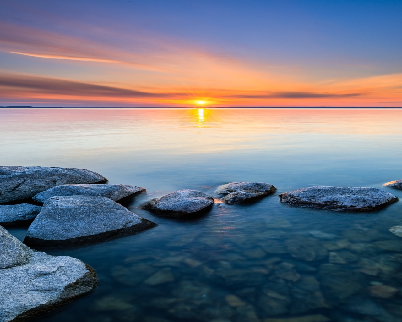 Большие камни в воде на закате яркого летнего солнца 