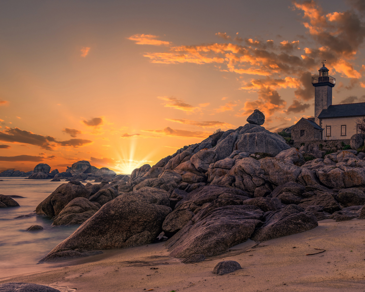 Маяк на берегу каменного берега на закате 