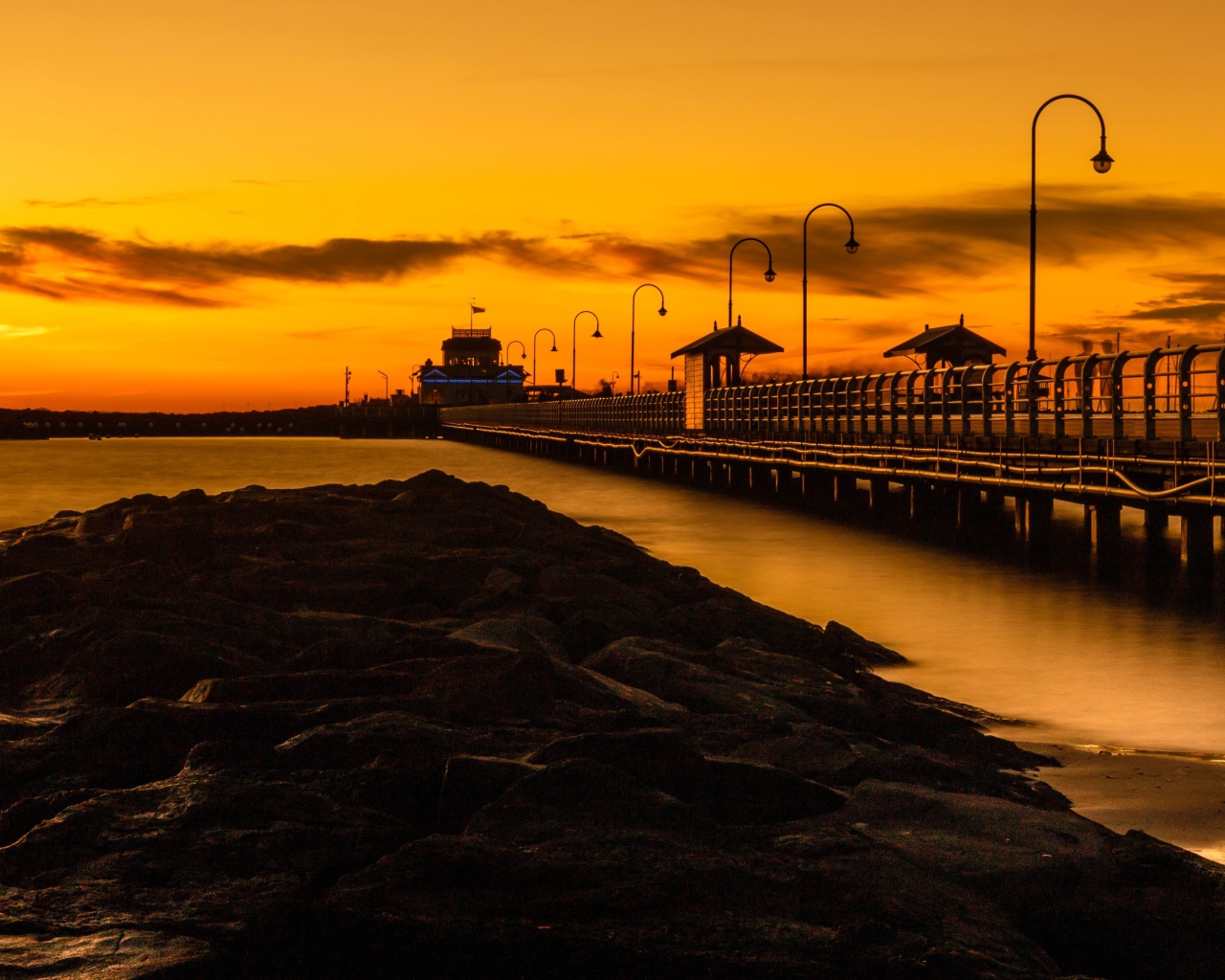 Длинный мост на морском побережье на закате 