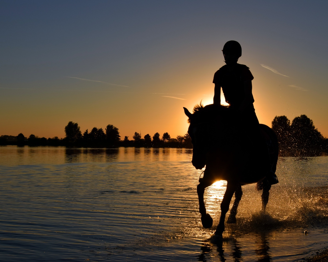 Девушка на лошади скачет по воде на фоне заката
