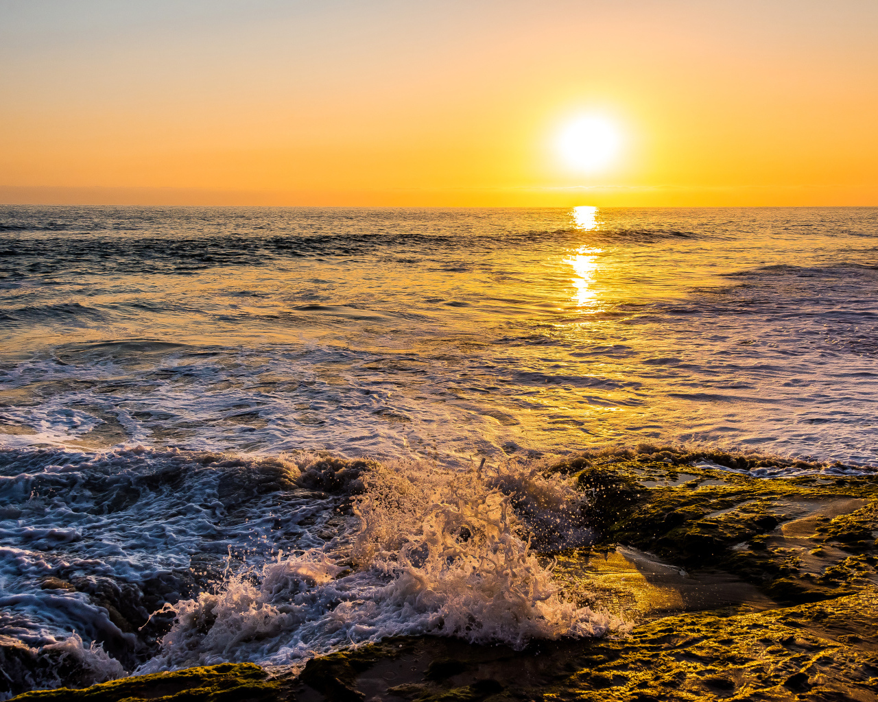 Белые волны бьются о берег на закате 