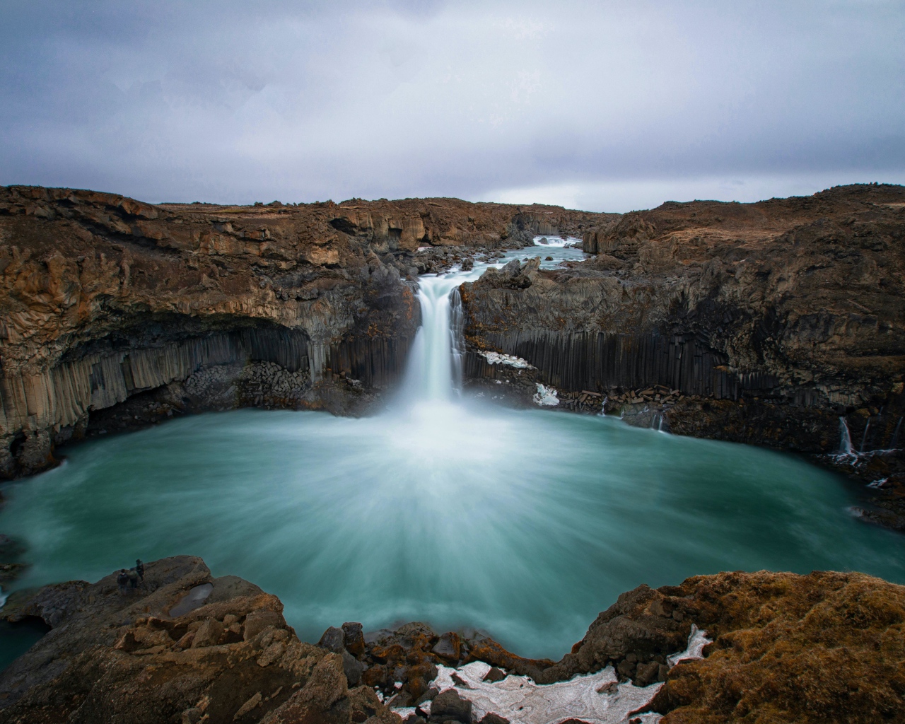Красивый водопад стекает с каменной скалы в озеро 