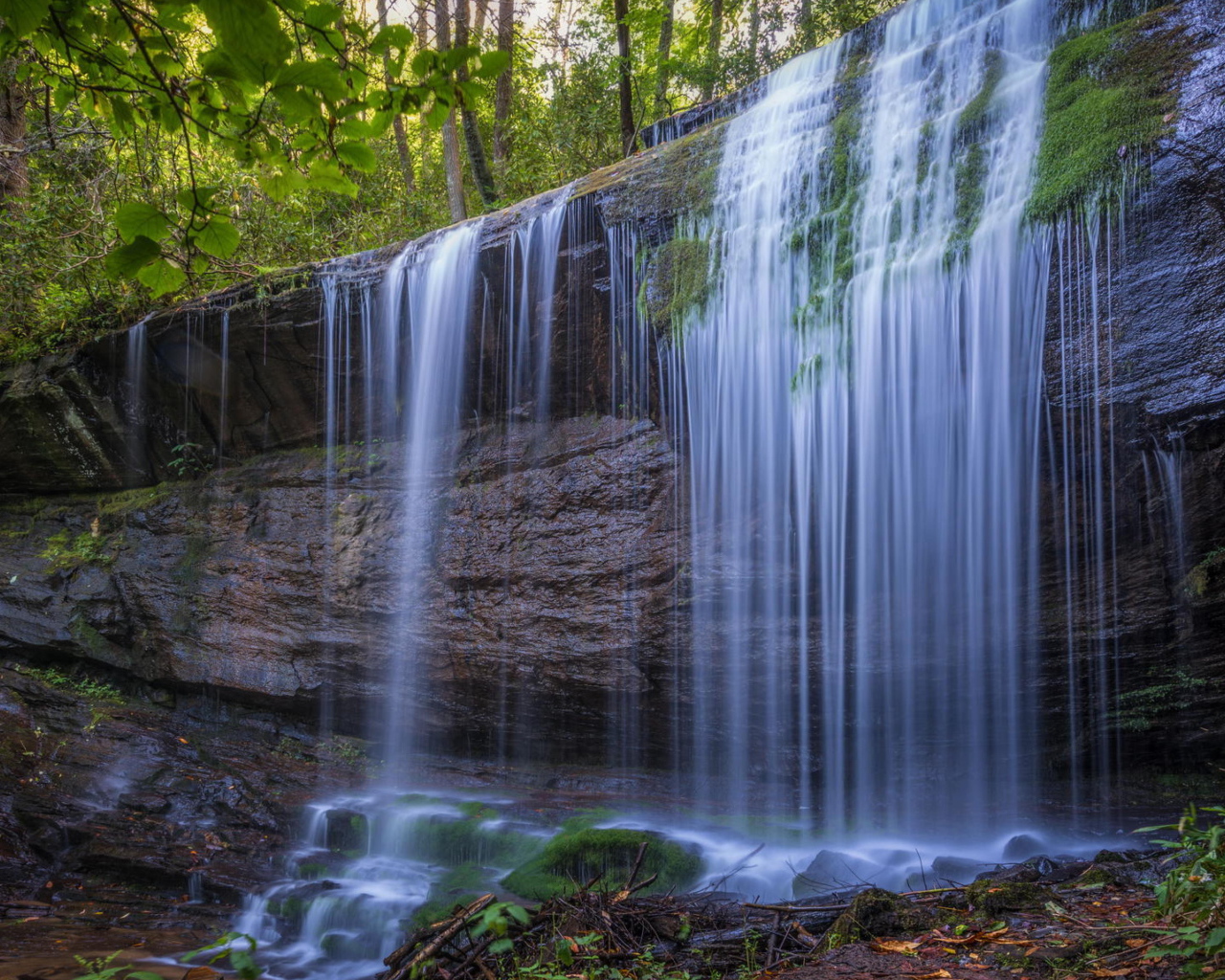 Холодная вода водопада стекает по мокрой скале