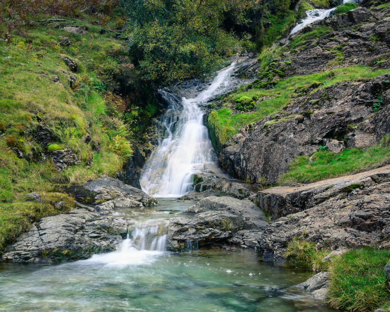 Горный ручей стекает по камням в реку 