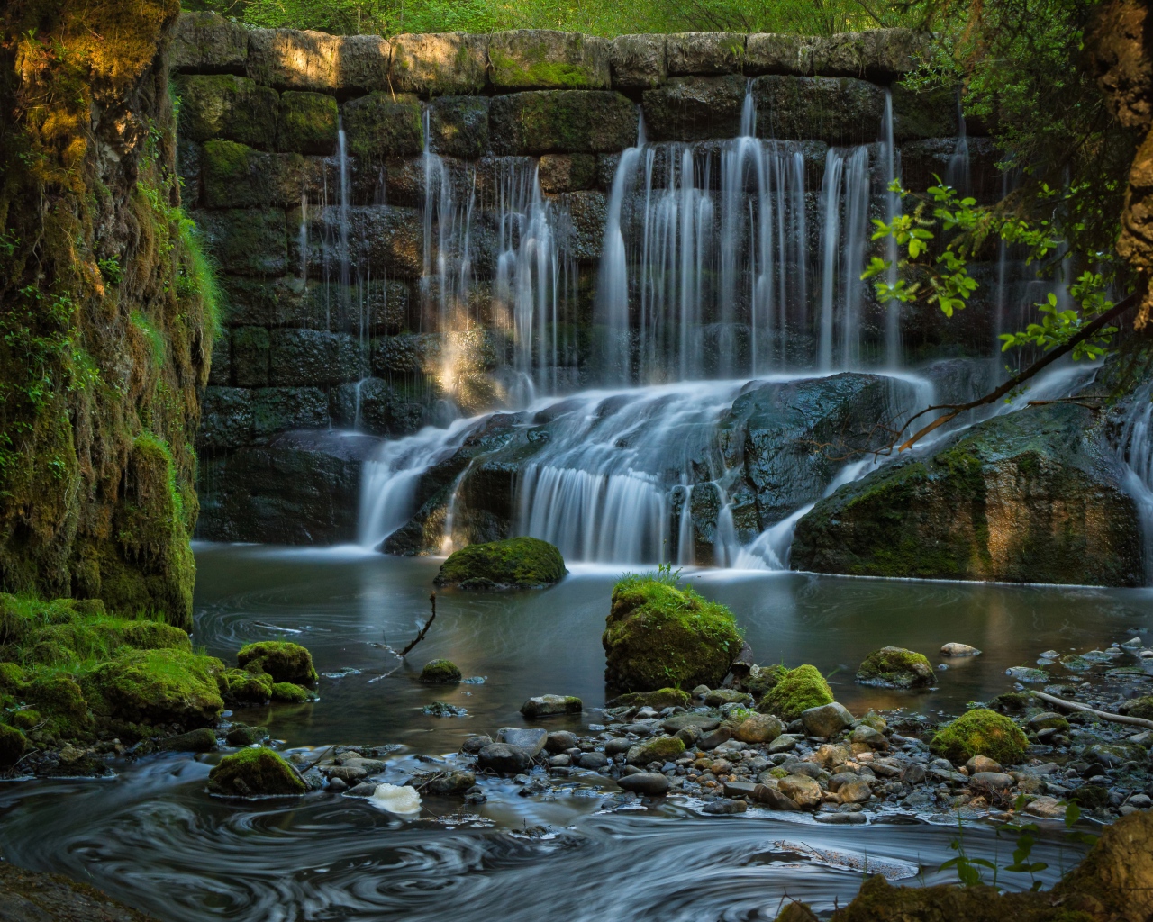Водопад пробивается сквозь покрытые мхом камни 