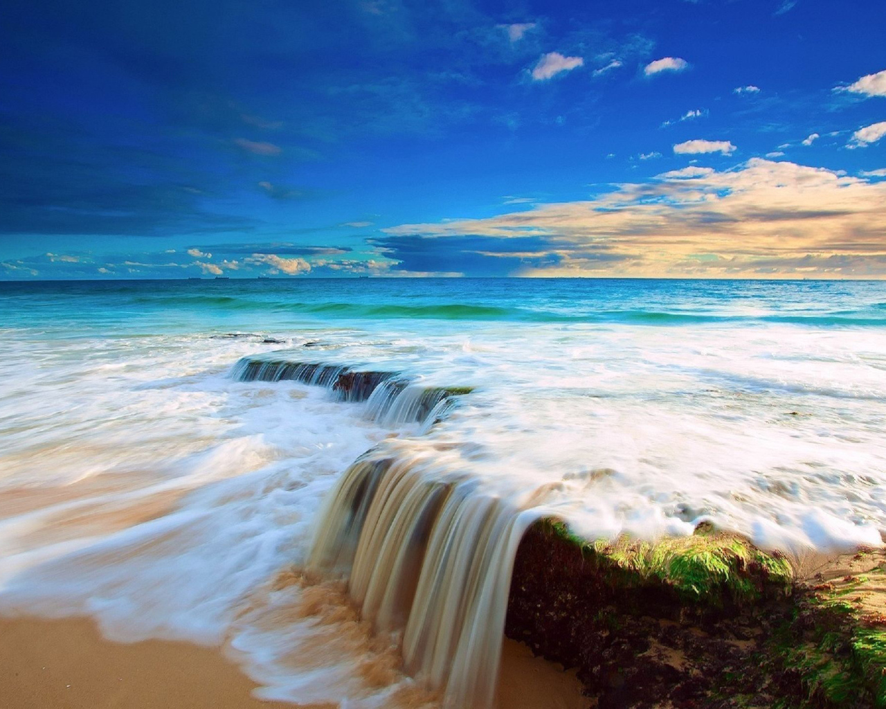 Белые волны бушующего океана на песке под голубым небом