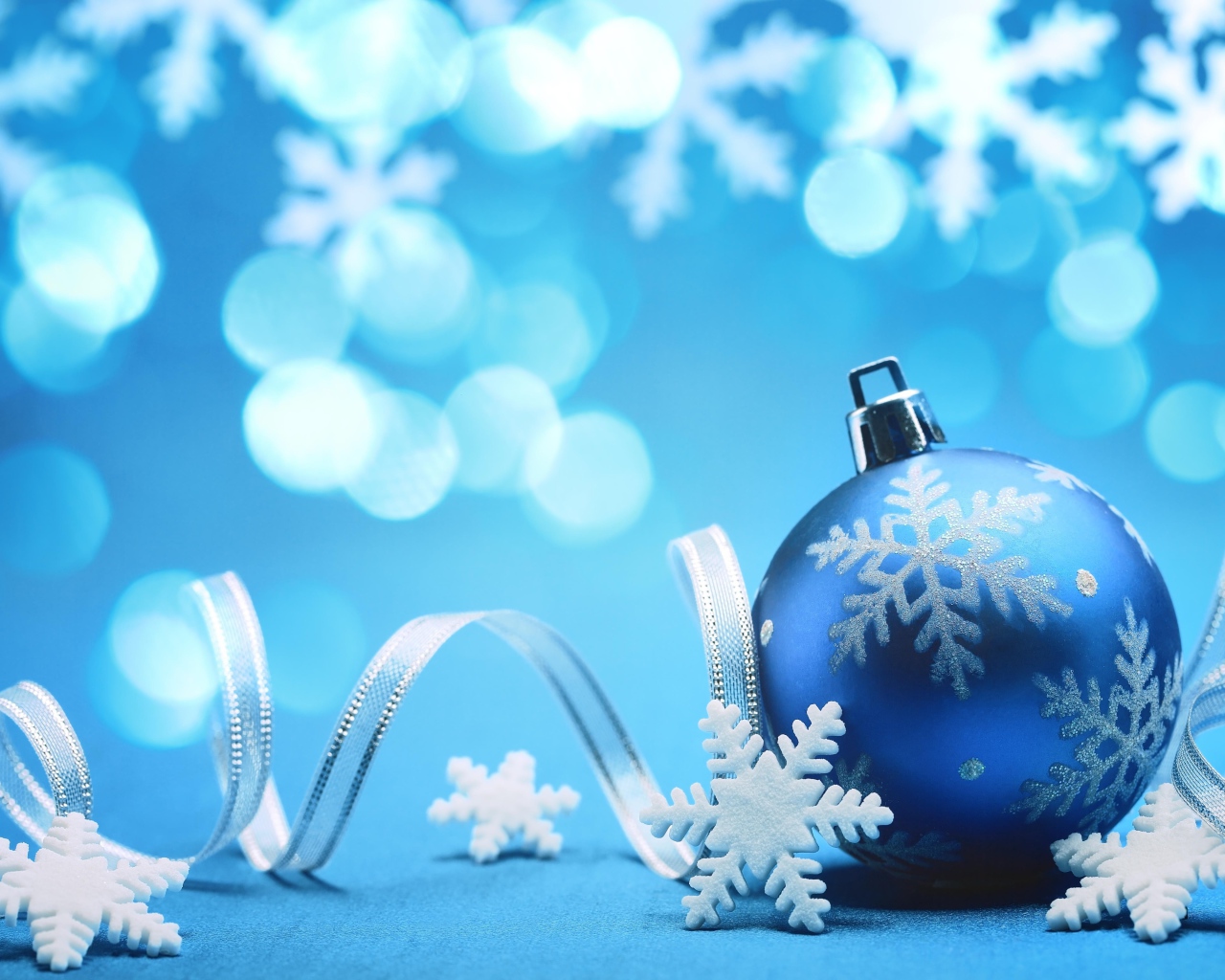 Красивый синий елочный шар с лентой и снежинками на Новый год 