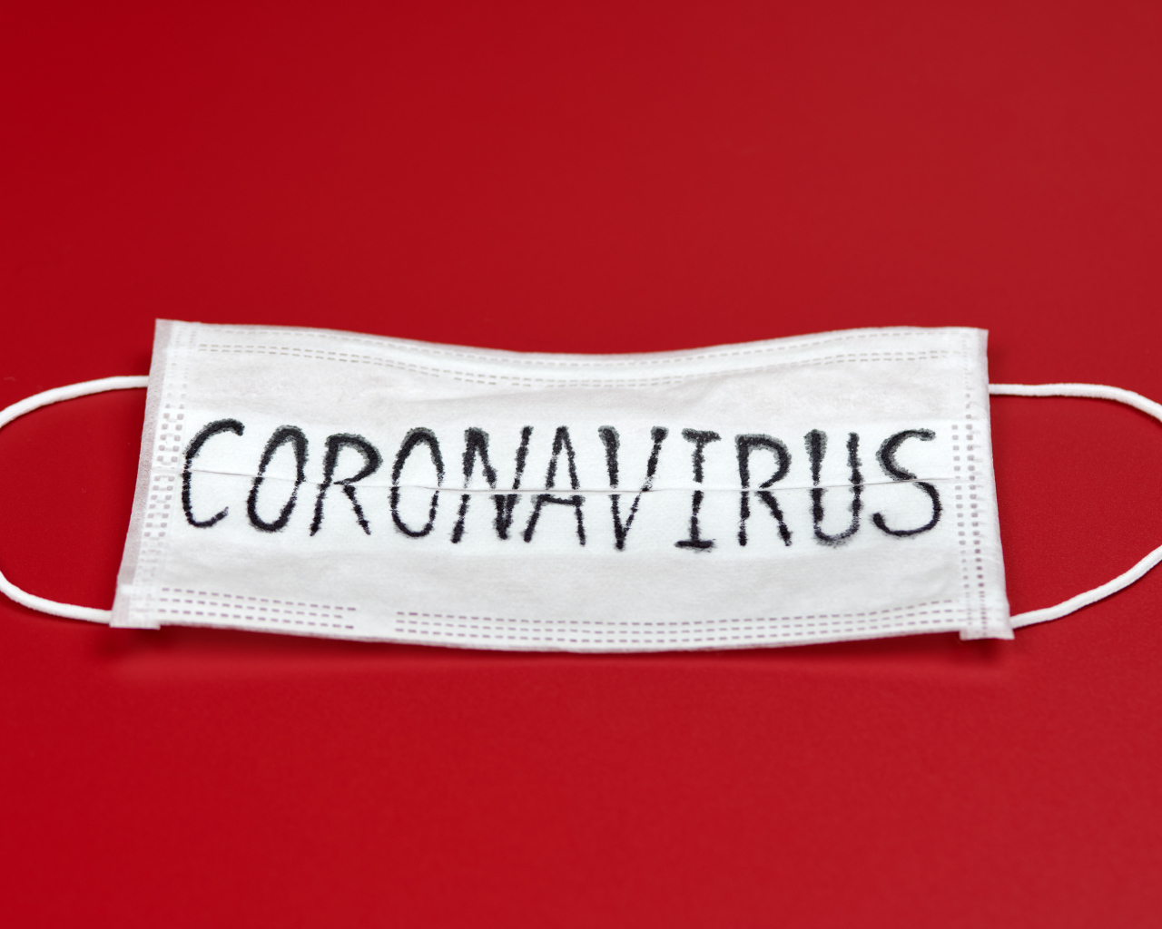 Medical mask with the inscription coronavirus Covid-19 on a red background