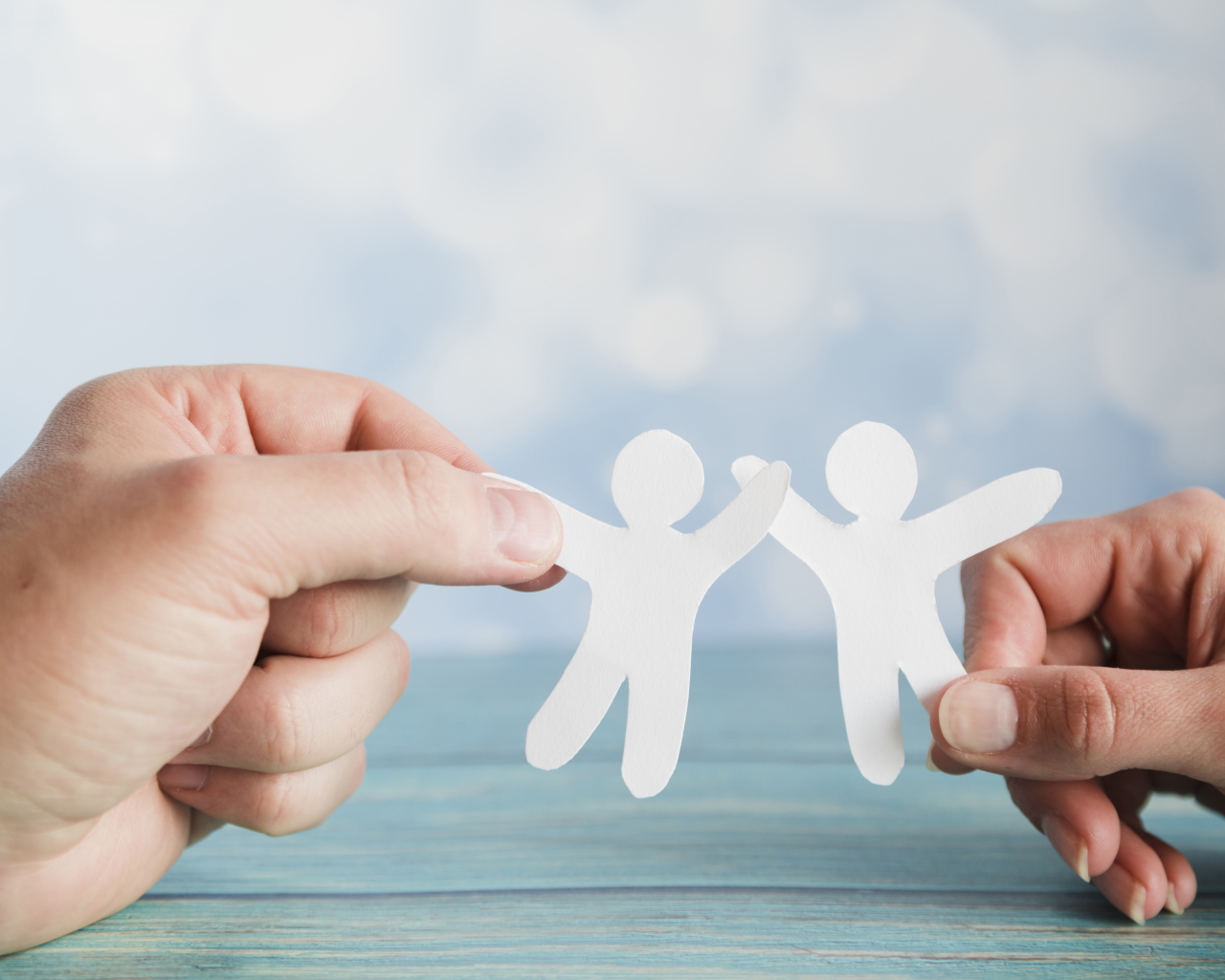 Два бумажных человечка в руках 