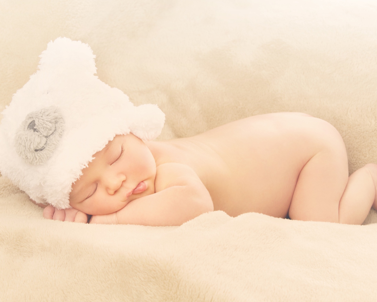Грудной ребенок с белой шапке спит на кровати