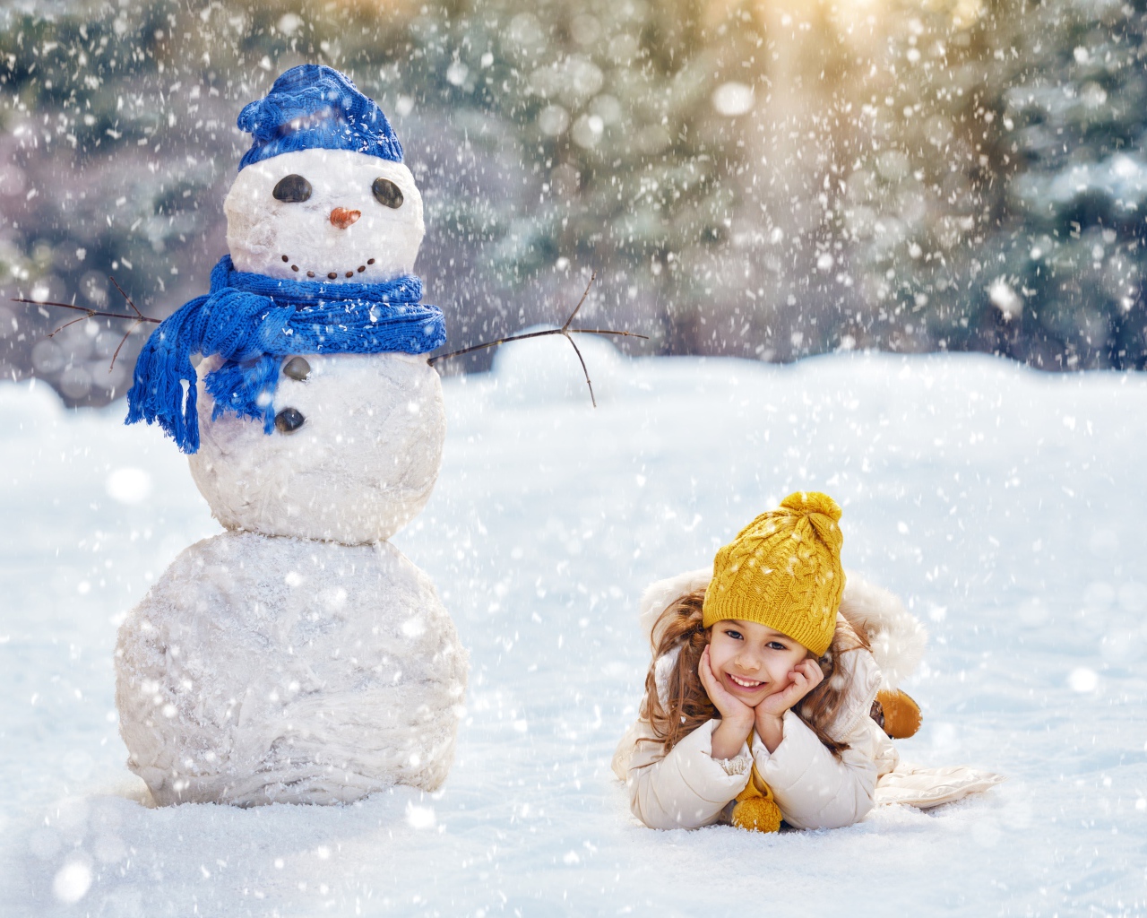 Милая девочка лежит на снегу у снеговика зимой