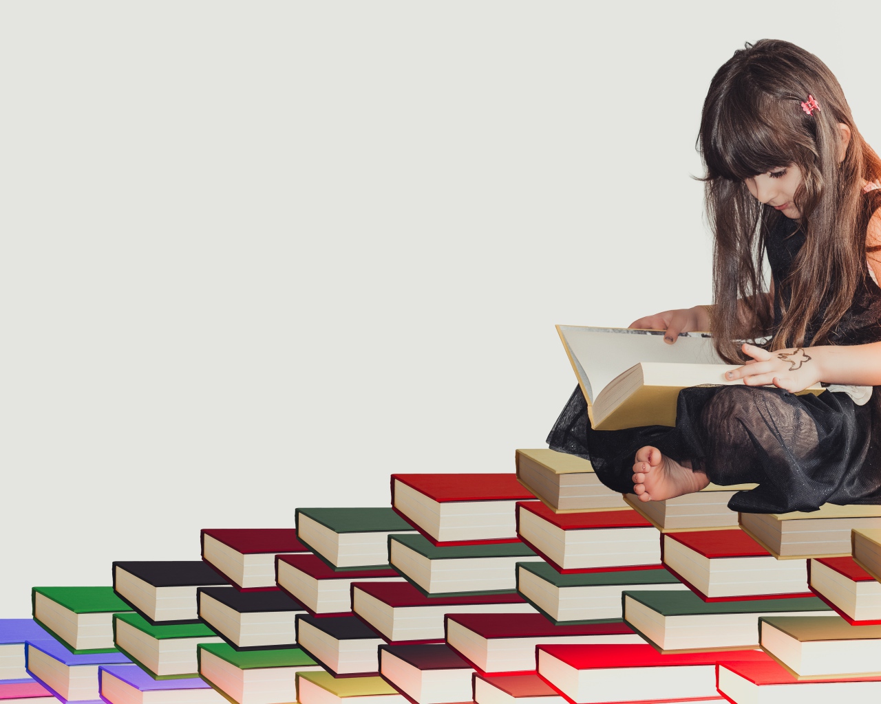 Маленькая девочка сидит на горе книг 