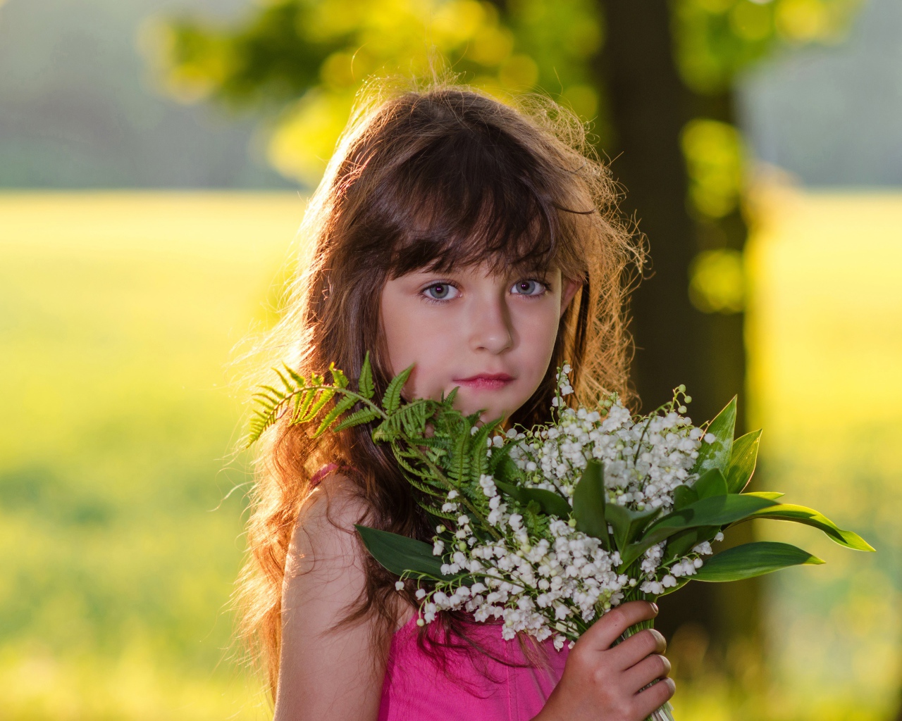 Красивая маленькая девочка с букетом ландышей в руке