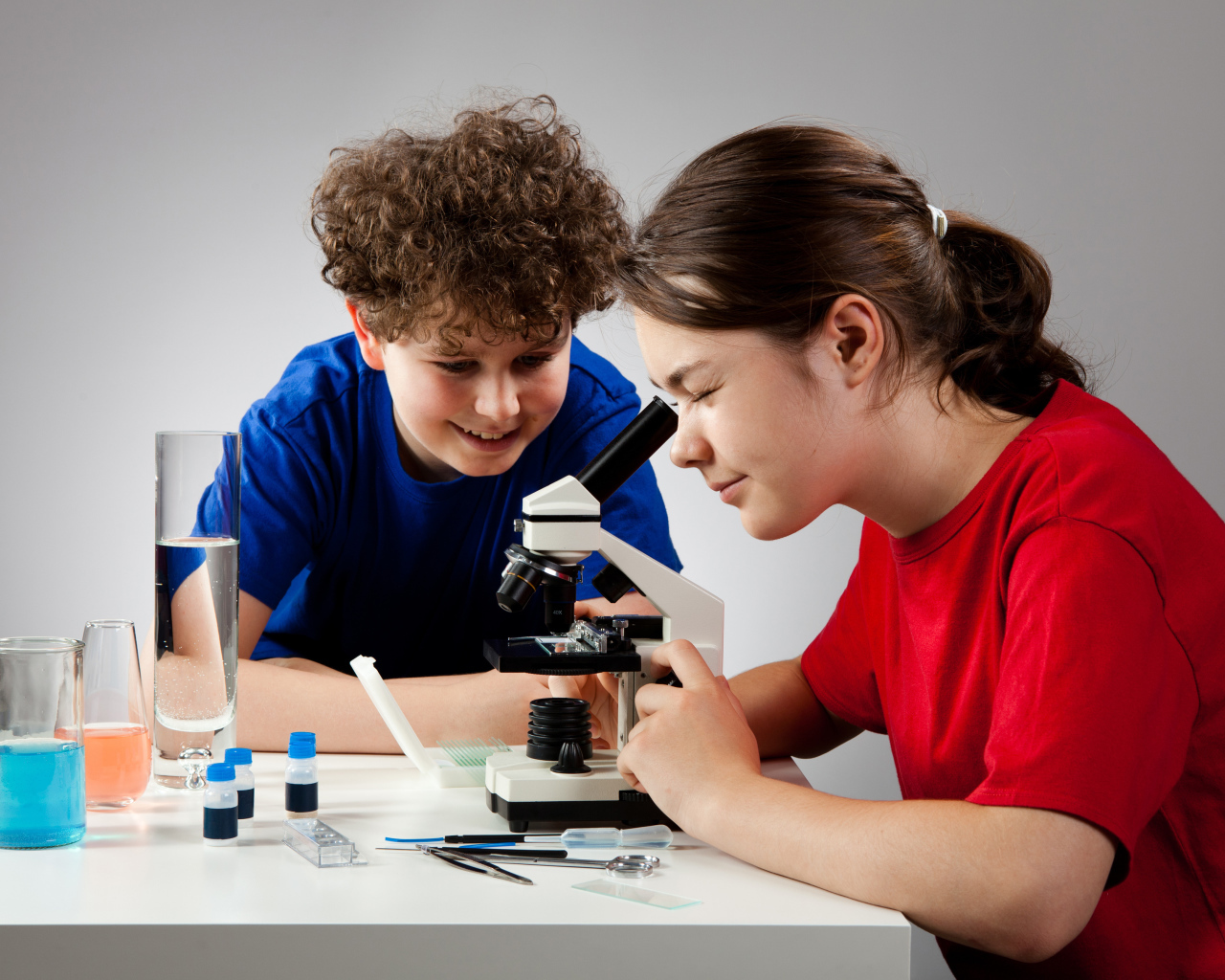 Мальчик и девочка смотрят в микроскоп 